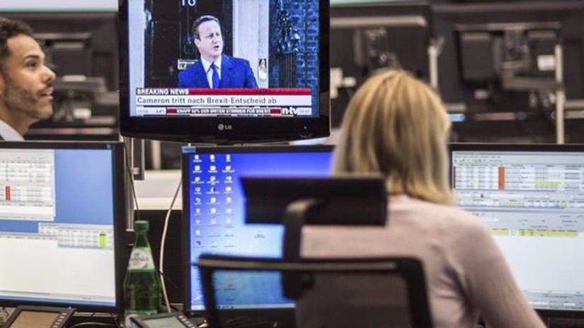 Una mujer observa la evolución del DAX 30 mientras escucha la comparecencia del primer ministro británico, David Cameron, en el parqué de Fráncfort (Alemania).