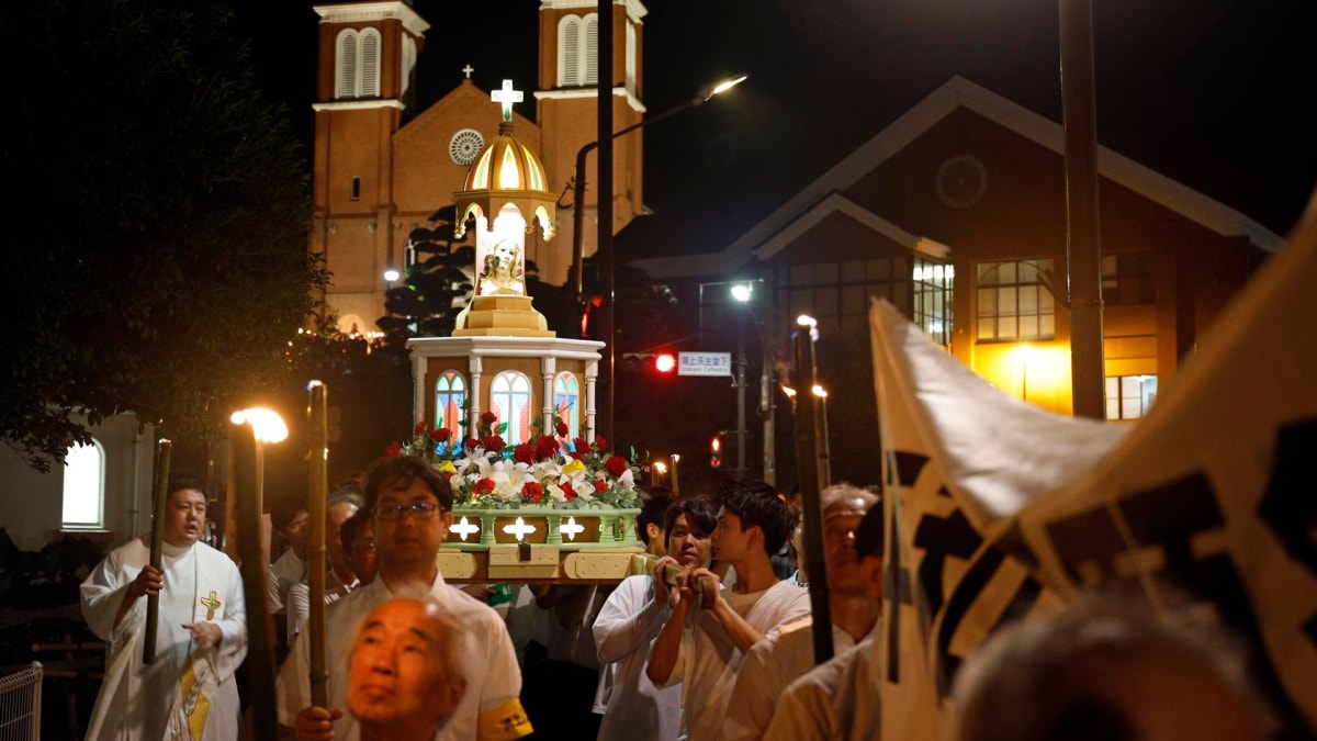 Unas personas transportan una plataforma con una estatua de la Virgen María que quedó expuesta al bombardeo atómico, durante una procesión con antorchas desde la catedral de Urakami hasta el parque Hipocentro en Nagasaki, al suroeste de Japón, el 9 de agosto de 2025, día del 80.º aniversario del bombardeo atómico. 