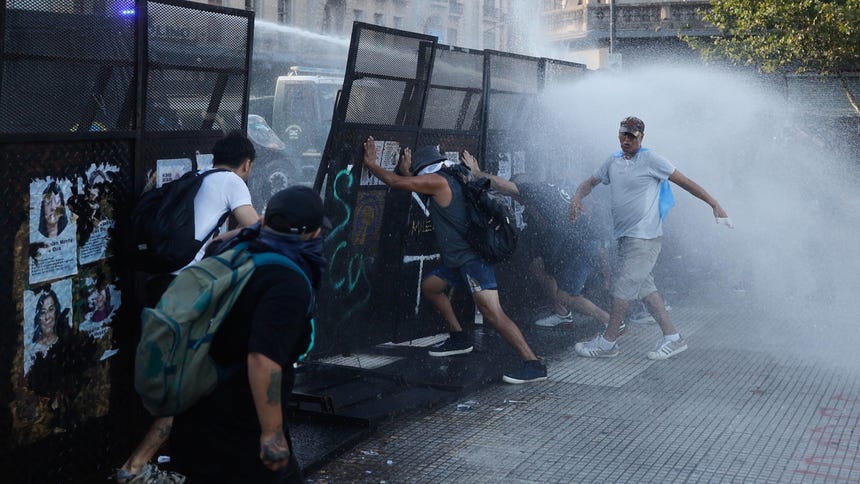 Manifestantes se cubren en un enfrentamiento con la policía durante una protesta contra la reforma laboral propuesta por el Gobierno de Javier Milei, este jueves, en Buenos Aires (Argentina).