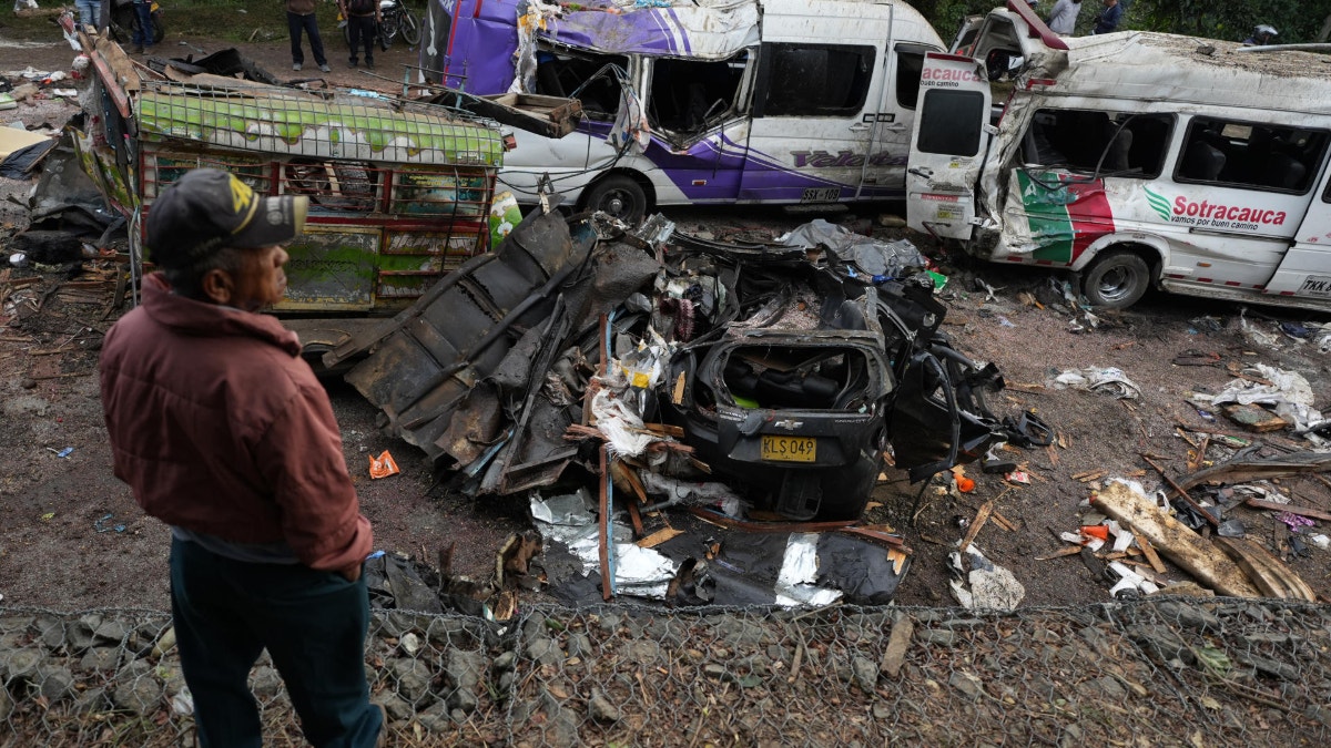 Personas observan este domingo vehículos destruidos por un atentado ocurrido en la Vía Panamericana en Cajibío (Colombia).