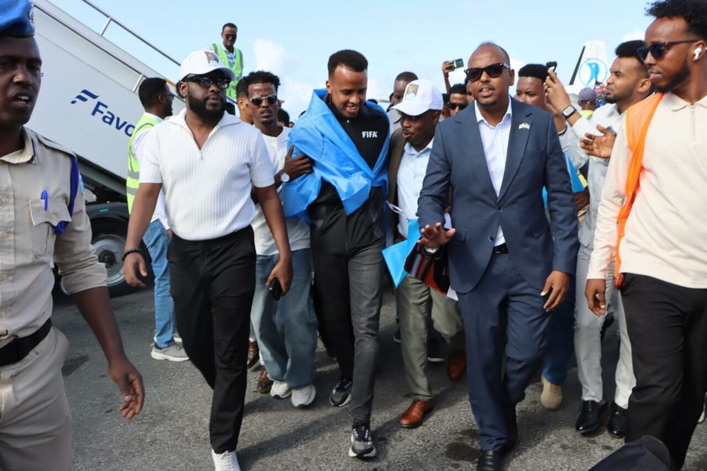 Embutido en un chándal negro de la FIFA, el árbitro recibió ramos de flores y una gran bandera nacional que se acabó poniendo a modo de capa.