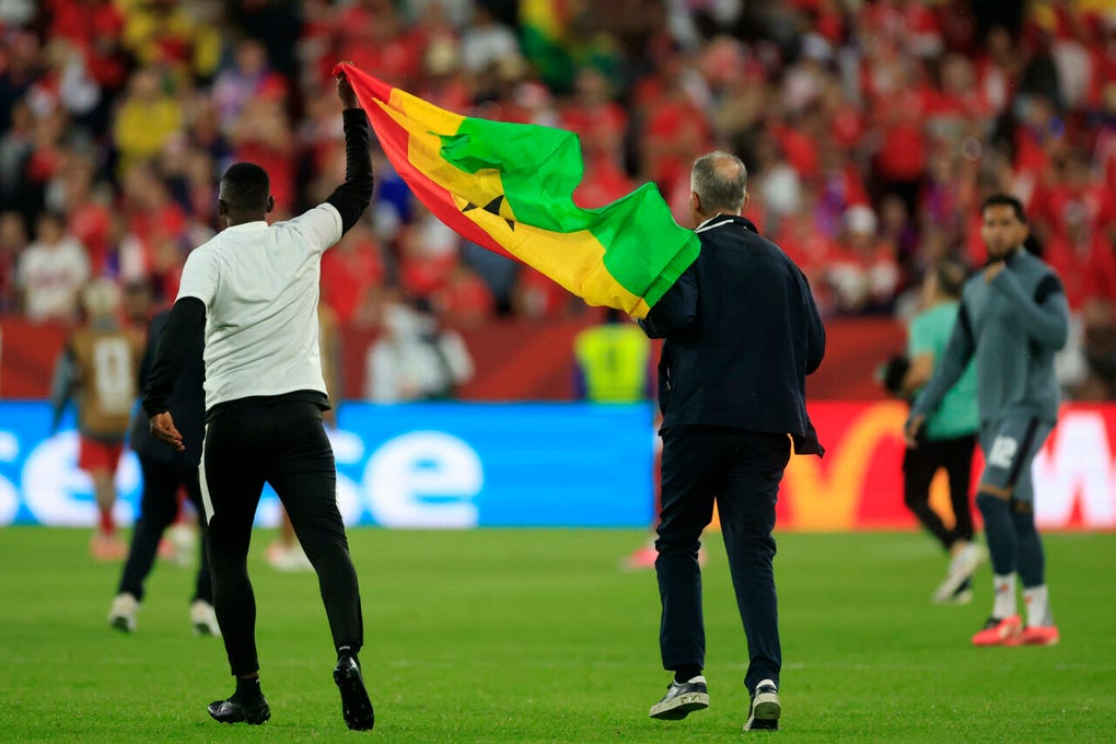 Miembros del comando técnico saltan al gramado de juego con la bandera de Ghana tras la victoria sobre Panamá.