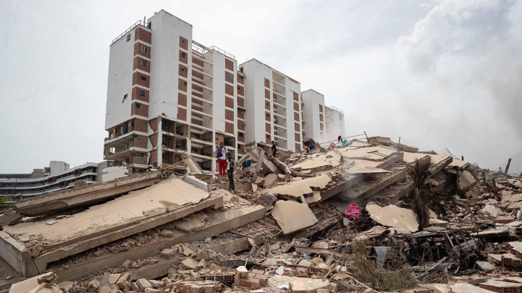 Personas caminan por escombros de edificios afectados por los terremotos en La Guaira.