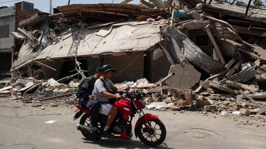Personas transitan frente a edificios afectados por terremotos este jueves, en Catia La Mar (Venezuela). El presidente del Parlamento de Venezuela, el chavista Jorge Rodríguez, informó que los fallecidos por los dos terremotos ocurridos el miércoles en su país ya dejan 920 muertos y 3.360.