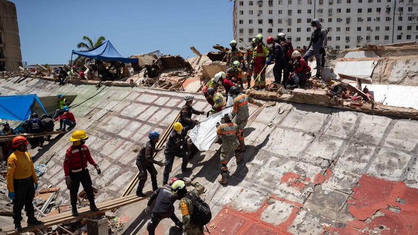 Rescatistas recuperan un cuerpo de los escombros de un edificio afectado por los terremotos en La Guaira.