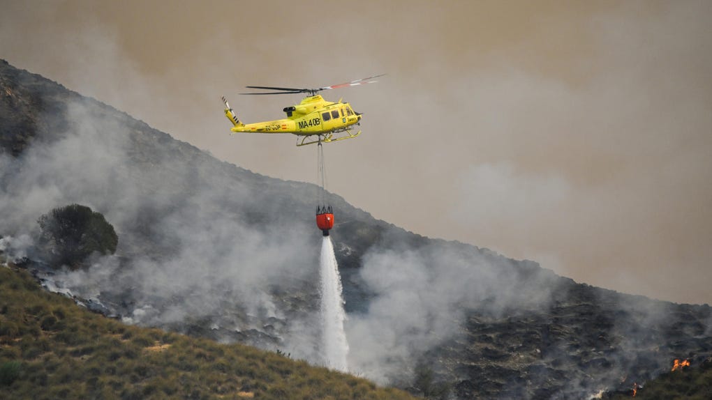 Un helicóptero del servicio de extinción de incendios arroja este viernes agua sobre uno de los focos del incendio forestal declarado en Los Gallardos, Almería, que se ha convertido en una tragedia sin precedentes en la zona y uno de los más graves de España, con un balance provisional de 12 personas fallecidas, ocho heridas y 19 desaparecidas.