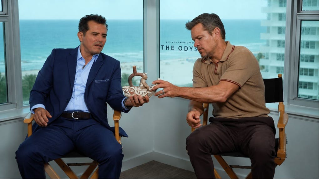 John Leguizamo y Matt Damon reciben con admiración un caballito de totora peruano durante la promoción de 'La Odisea'.