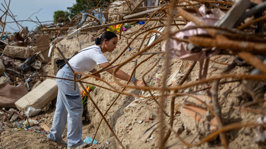 Una mujer deja flores en un altar improvisado durante una misa por las víctimas del doble terremoto de magnitud 7,2 y 7,5 de hace un mes en Venezuela que no han podido ser recuperadas en el edificio 'La Estrella', el último lunes en Macuto (Venezuela).