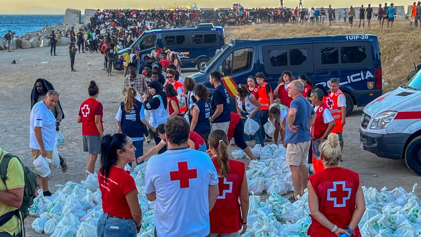 Miembros de la Cruz Roja de Ceuta reparten bolsas de comida a personas migrantes el último martes, en la playa ‘El Trampolín’ de Ceuta.