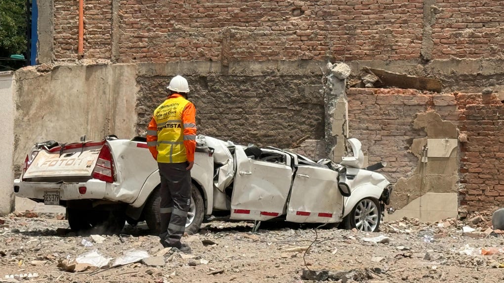 Un hombre observa un carro destruido este sábado en el barrio Cuarto de Legua, en Cali.