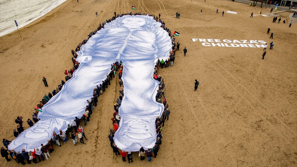 Despliegue de una lona con el retrato de Hind Rajab, la niña fallecida en Gaza, en un acto conmemorativo en Barcelona, España. 