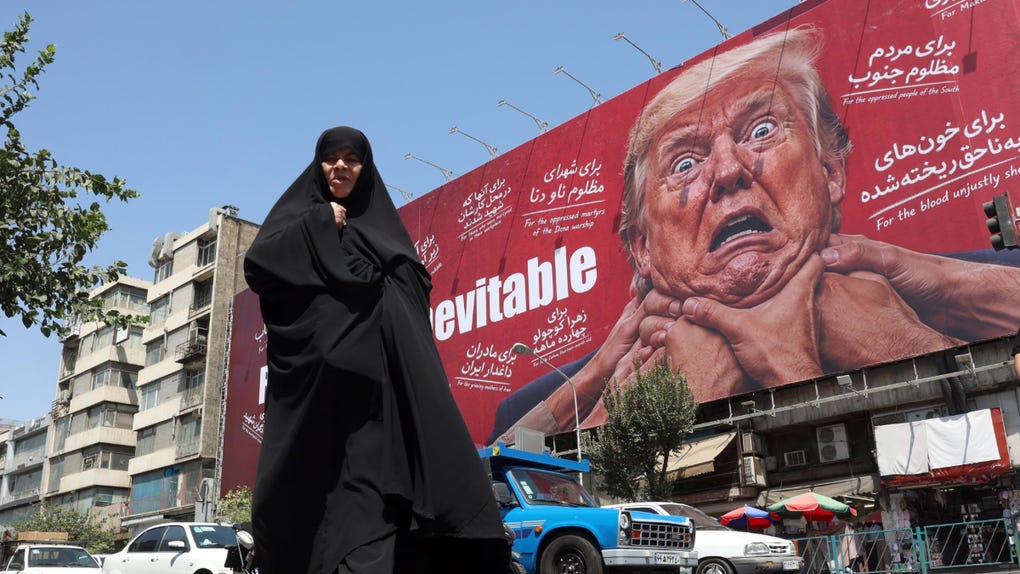 Una mujer camina junto a una valla publicitaria contra Trump en Teherán.
