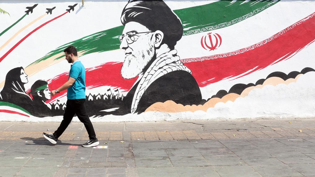 Un iraní camina aal lado de un mural con la imagen del fallecido ayatolá Ali Jamenei en una calle de Teherán. 