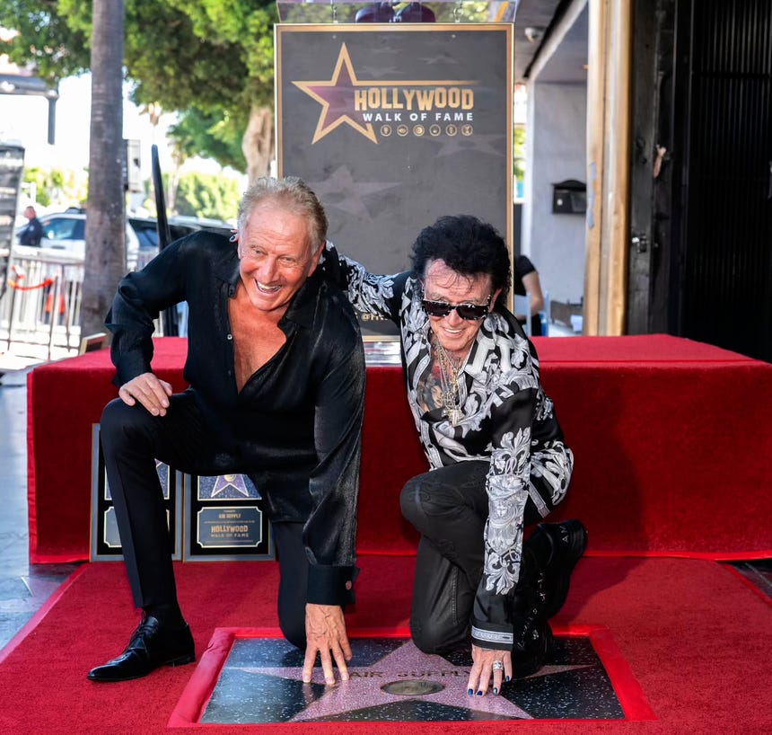 Los músicos Graham Russell y Russell Hitchcock posando con su estrella en Hollywood.