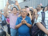 Devotos del Señor de Los Milagros ven el paso de la imagen en el Centro de Lima.